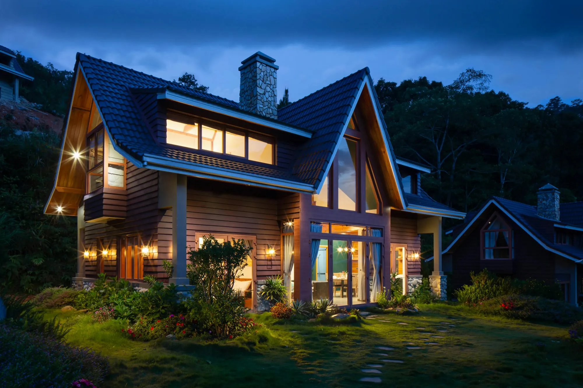 Two-story home glowing with lit windows at dusk